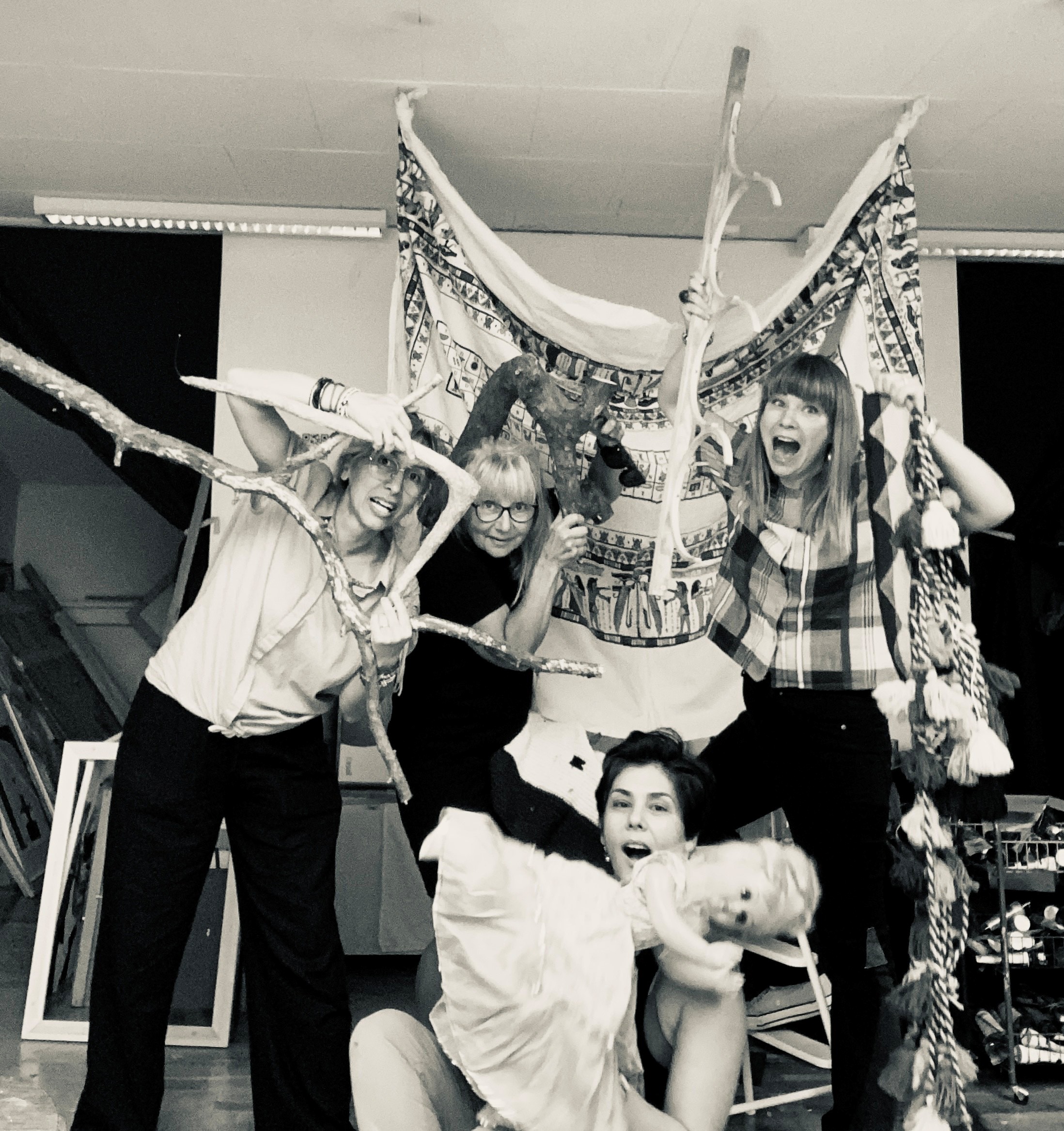 fyra glada konstnärer med textil, grenar och en docka